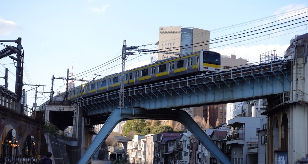 a yellow and white train traveling over a bridge