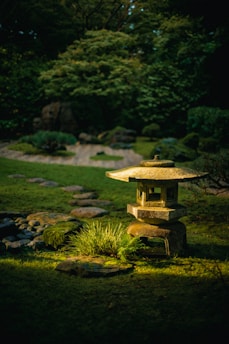 a stone lantern in the middle of a grassy area