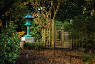 A serene Japanese garden corner with a stone lantern surrounded by lush greenery and delicate cherry blossoms.