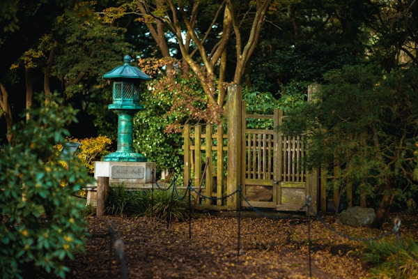 A serene Japanese garden corner with a stone lantern surrounded by lush greenery and delicate cherry blossoms.