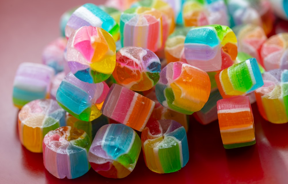 a pile of multicolored candies on a red surface