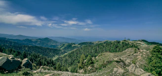 A panoramic view of Eswatini’s lush green valleys and rolling hills under a bright blue sky.