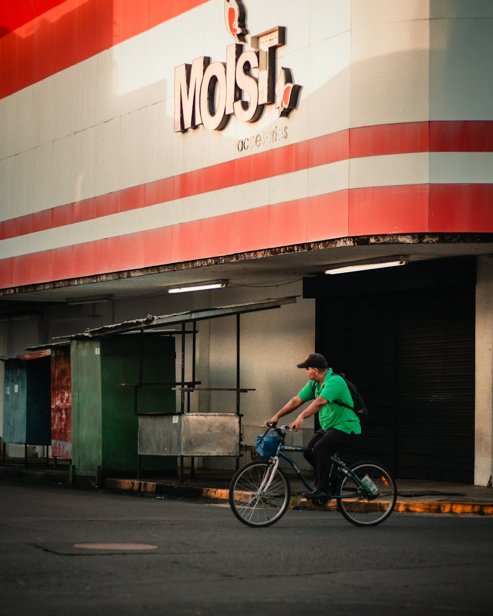 a man riding a bike down a street past a store