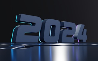 Bold 3D numbers displaying '2024' with a modern, futuristic design. The numbers appear on a glossy, reflective surface against a dark background. Subtle lighting accents create a sleek and sophisticated look.