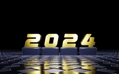Golden numbers form the year 2024, displayed prominently on a reflective, checkered surface. The background is predominantly black, emphasizing the metallic sheen of the numbers.