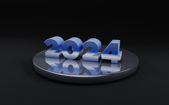 A metallic, reflective platform displays the numbers '2024' in a glossy blue finish. The numbers are prominently centered and cast reflections on the platform, creating a futuristic and sleek appearance.