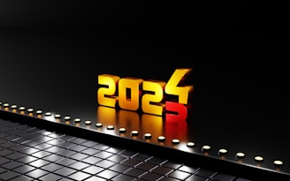 3D gold numbers forming the year 2024 stand prominently against a black reflective surface. The number 3 is falling away, indicating a transition from 2023 to 2024. Small circular lights line the edge, creating a futuristic feel.