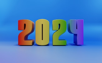 A colorful and bold representation of the year '2024' with each digit in a distinct color, set against a smooth blue gradient background. The numbers are 3D, giving them a strong and prominent appearance.