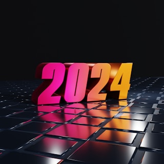 Large, colorful 3D numbers spelling out '2024' resting on a grid of reflective, metallic square tiles. The numbers transition from pink to orange, standing out against a dark background.