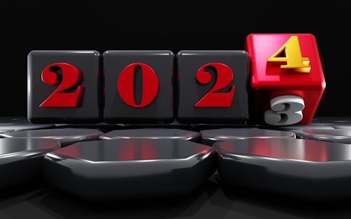 A sequence of four black blocks with the numbers 2023, where the '3' block is rolling over to become '4', indicating the transition to 2024. The numbers are in red with the '4' in yellow on a red block. The background is dark, creating a striking contrast with the glossy blocks.