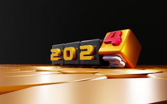 Golden numbers represent the year 2024 on a smooth reflective surface. Each digit is displayed on a cube, with the final number standing out in red.