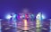 Large 3D numbers '2024' stand on a reflective tiled surface, illuminated by colorful lighting that casts a gradient across the scene. The background features a smooth gradient transitioning from blue to purple, complementing the shiny metallic look of the numbers.