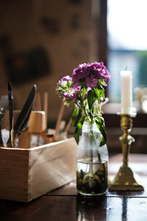 A promise box resting on a wooden table surrounded by fresh flowers and a lit candle.