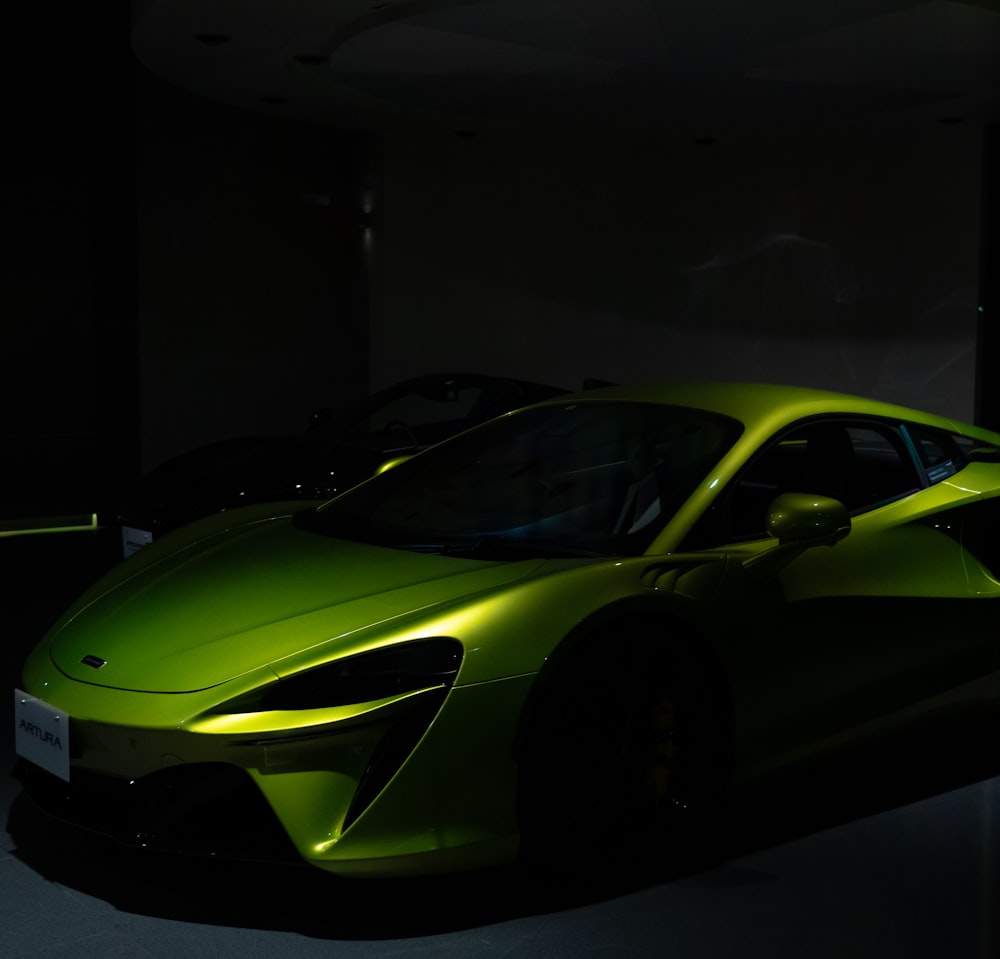 a green sports car parked in a dark room