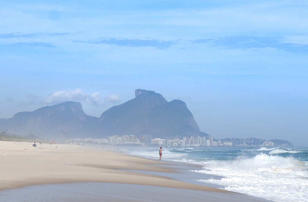 a person standing on a beach next to the ocean