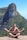 a man sitting on top of a rock with a mountain in the background