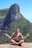 a man sitting on top of a rock with a mountain in the background