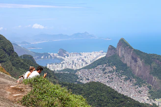 a couple of people sitting on top of a mountain