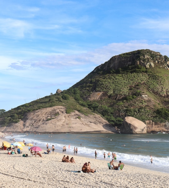 a group of people sitting on top of a sandy beach