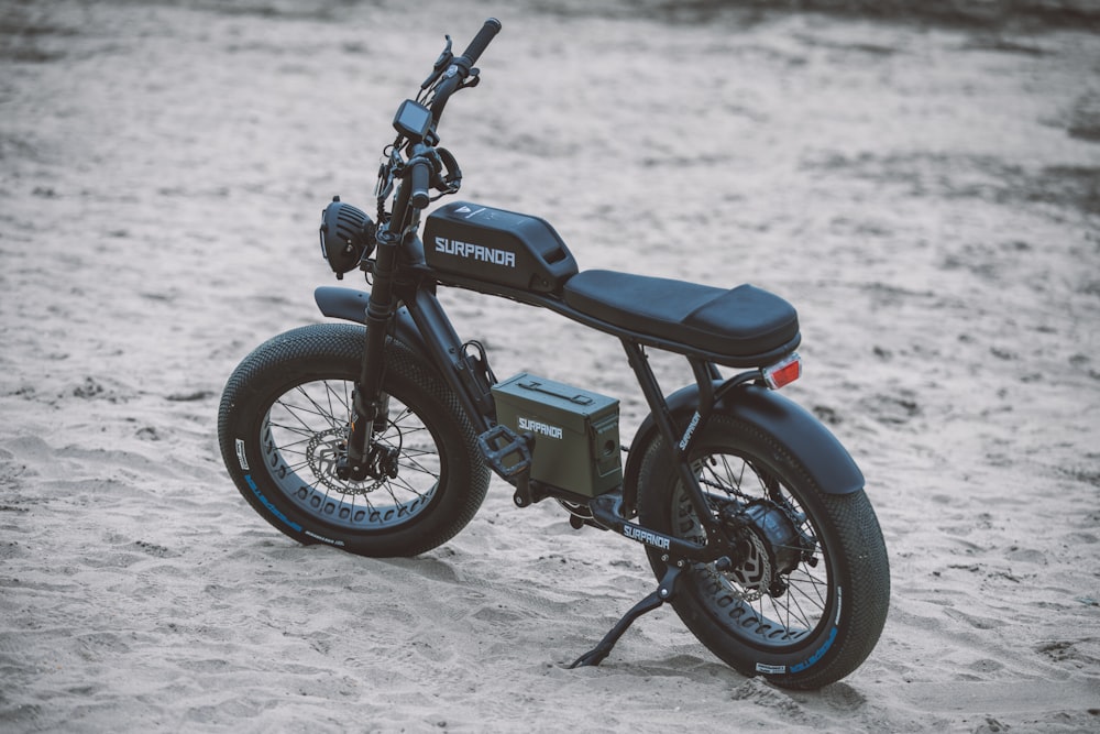 a black motorcycle parked on top of a sandy beach