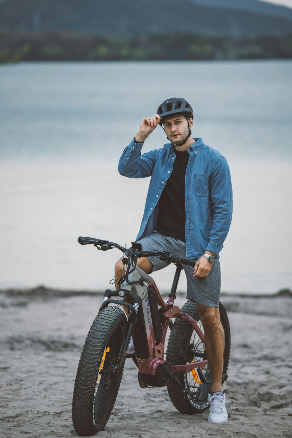 a man sitting on top of a bike on a beach