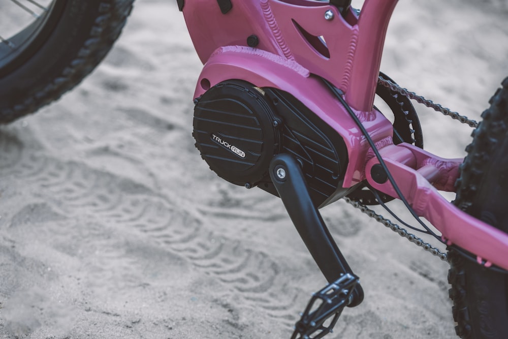 a close up of a pink bike on a beach