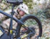 Close-up of a cyclist using a smart pump on a mountain bike tire outdoors.