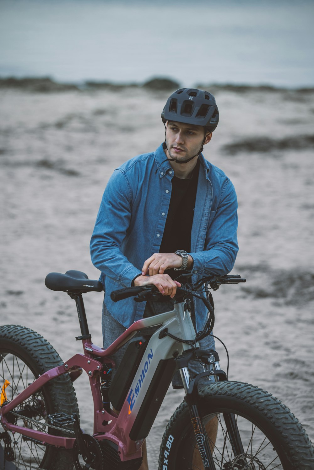 a man standing next to a bike on a beach