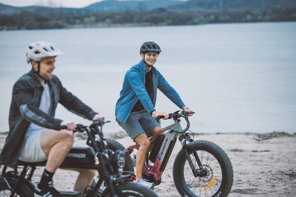 a man riding a bike next to another man on a beach