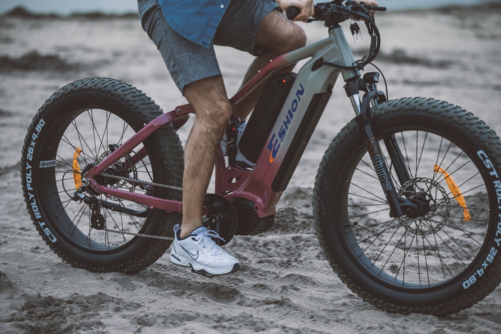 a man riding a bike on top of a sandy beach