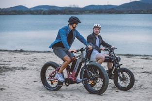 A group of friends riding electric bikes along the sunny Caparica coastline.