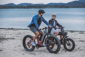 A group of riders on e-bikes cruising along a sunlit coastal trail with waves crashing nearby.