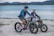 Couple riding electric bikes along a scenic coastal trail near Cape Coast.