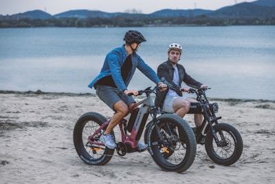 A group of riders on e-bikes cruising along a sunlit coastal trail with waves crashing nearby.