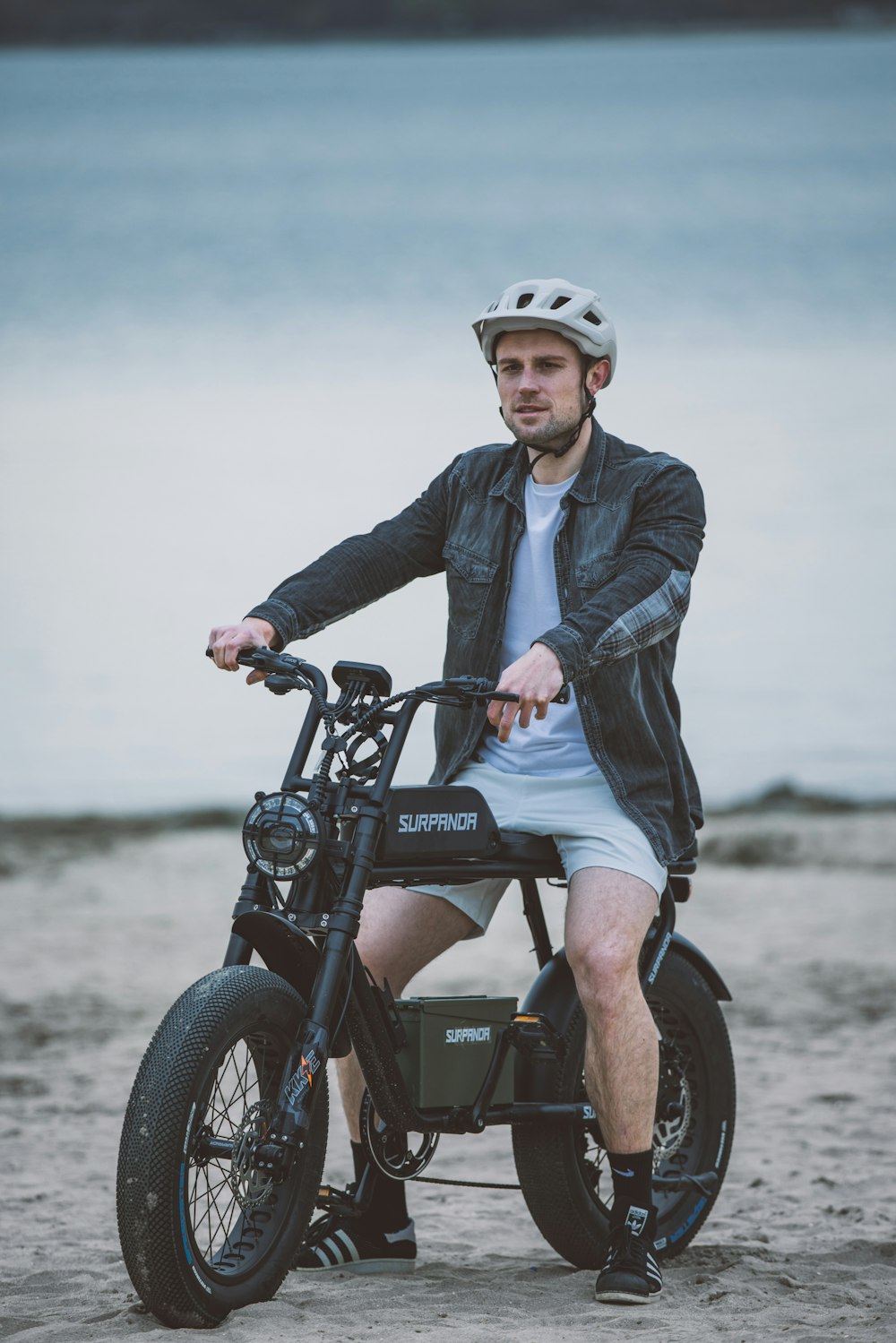a man sitting on a small motorcycle on the beach