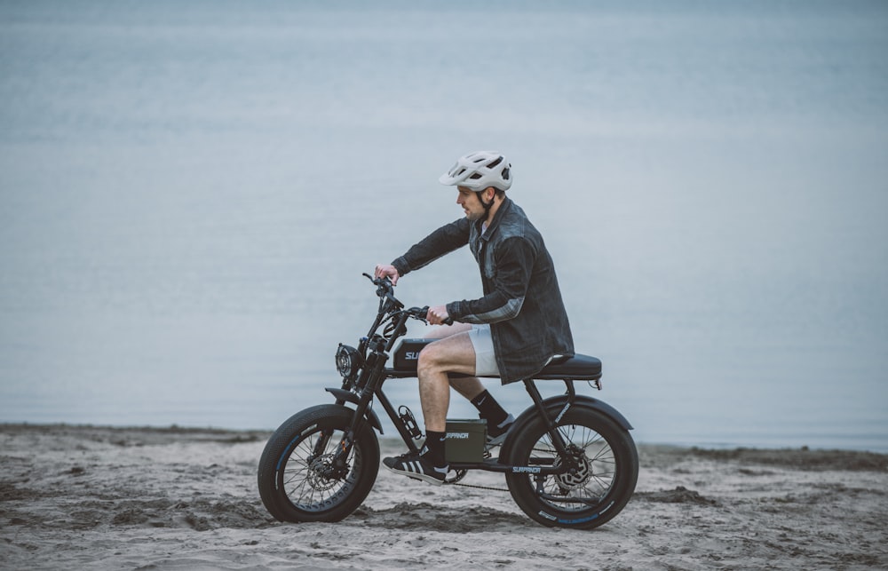 a man is riding a small motorcycle on the beach