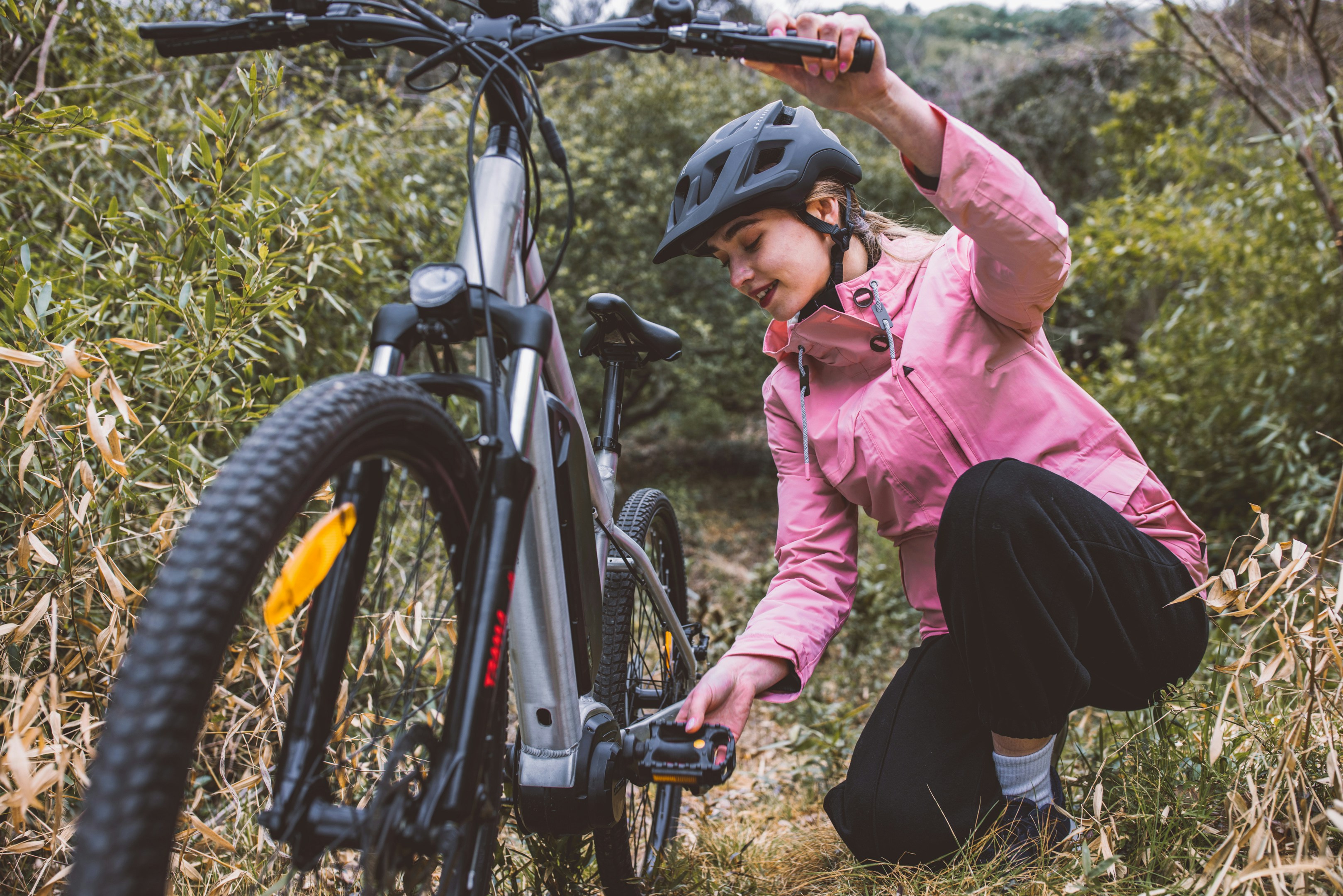 a woman in a pink jacket putting on a bicycle