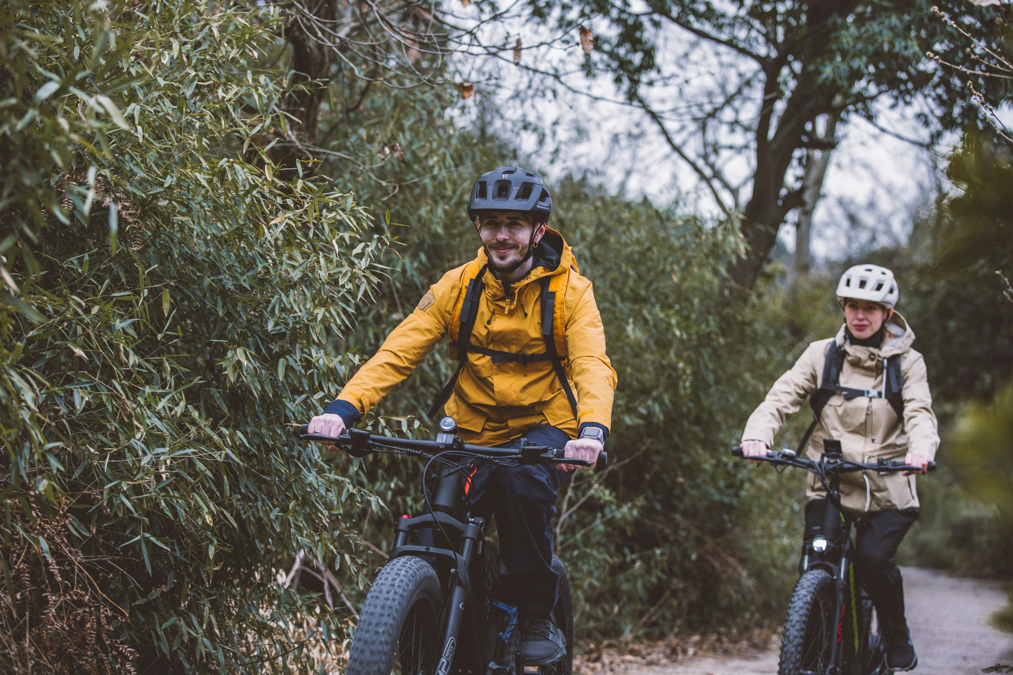 a couple of people riding bikes down a dirt road