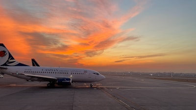 Sineh airport services vehicle parked by the airport runway during sunset.