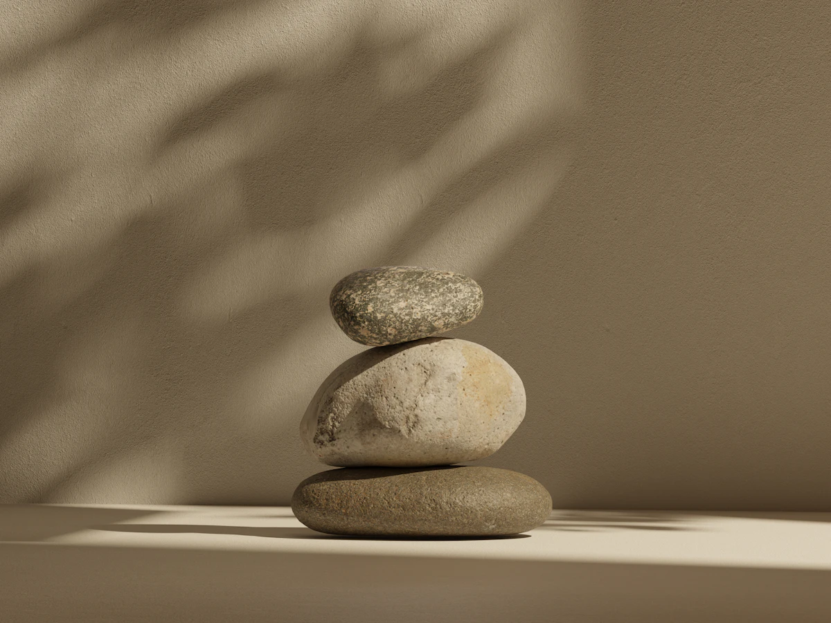 Three smooth stones stacked in soft afternoon shadow