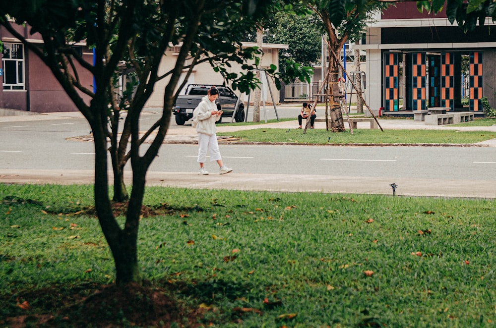 a man walking down a street next to a tree