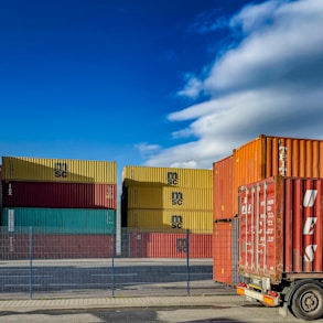 a truck is parked in front of a bunch of shipping containers