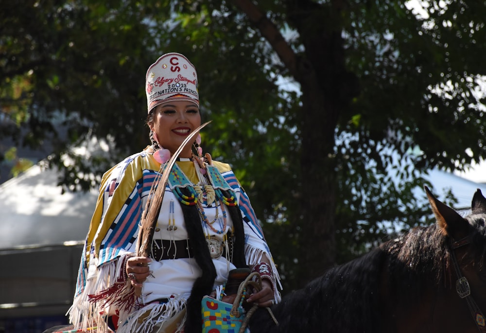 a woman in a native american outfit riding a horse