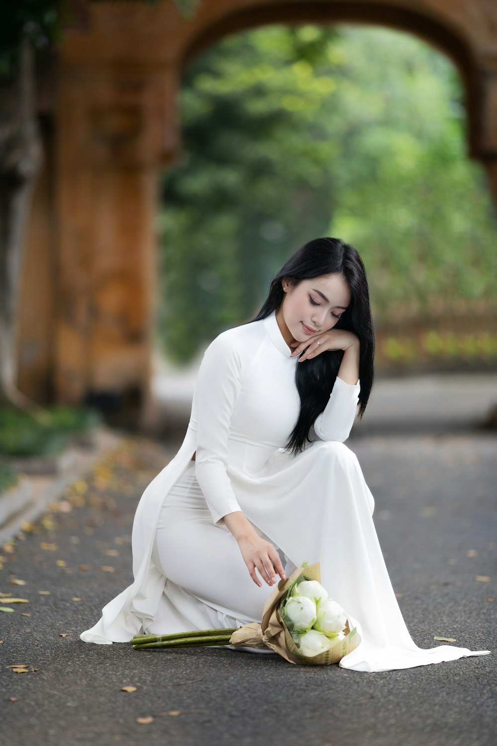 a woman kneeling down with a bouquet of flowers