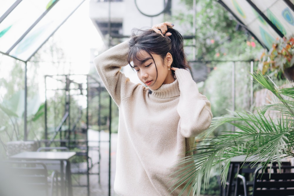 a woman standing in a greenhouse holding her hair