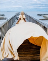 Side view of a model walking along the shore wearing a flowing lace cover-up.