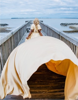 Side view of a model walking along the shore wearing a flowing lace cover-up.