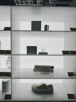 Trendy sneakers and luxury watches displayed on a minimalist wooden shelf.