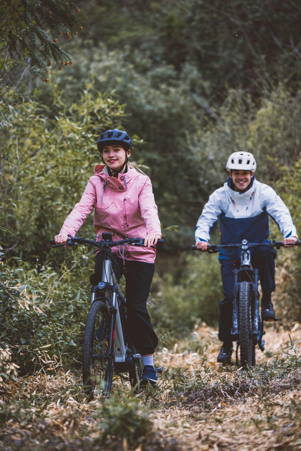 a couple of people riding bikes through a forest
