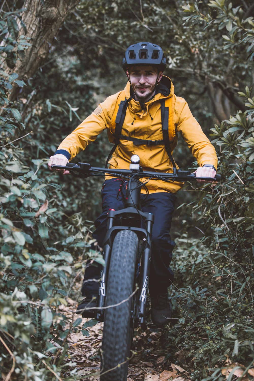 a man riding a bike through a lush green forest